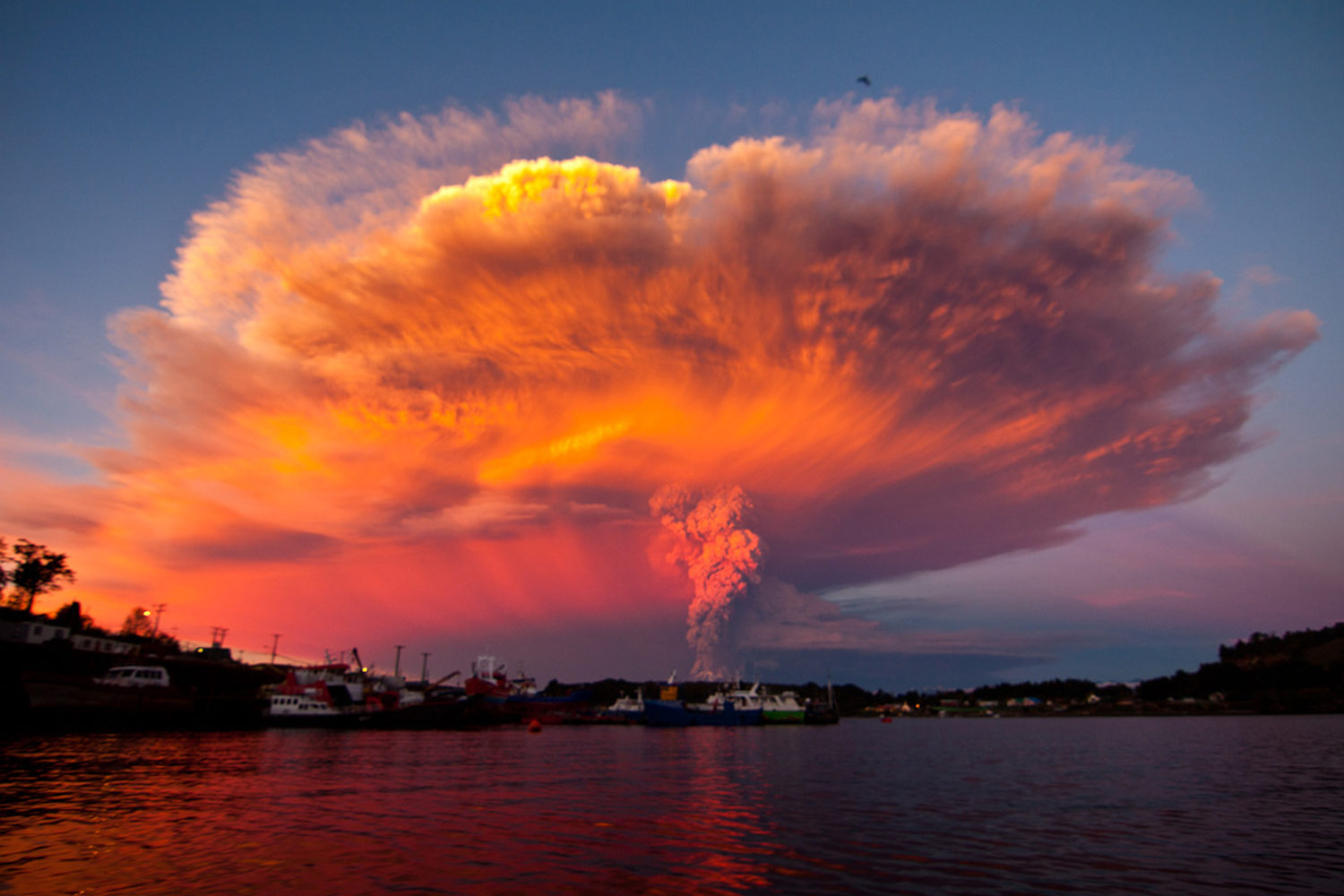 Beautiful photo of the eruption of the Calbuco volcano over Puerto Montt Harbor at sunset from a sailboat.