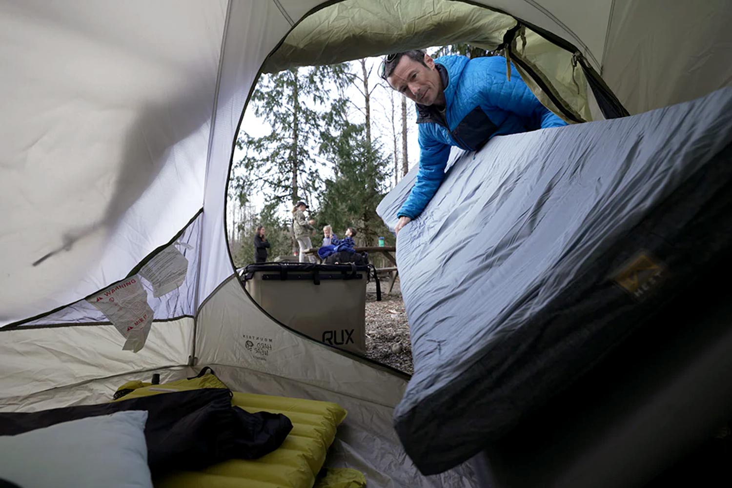 Jamie setting up camp with his family in the background.